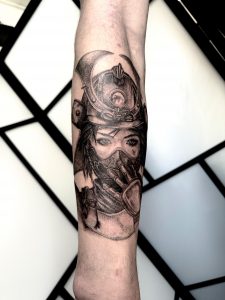 Illustratives Realismus-Tattoo: Frauenporträt mit Samurai-Helm und Maske am Unterarm