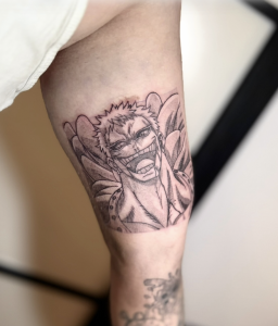 Anime Tattoo eines lachenden Charakters im Black-&-Grey-Stil am Oberarm